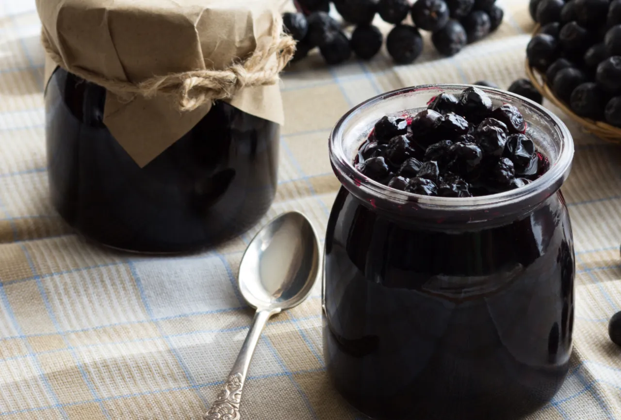 Słoiki z przetworami z aronii, gotowe do przechowywania. To świetny spos&oacute;b, jak mrozić aronię, by cieszyć się jej smakiem przez cały rok.