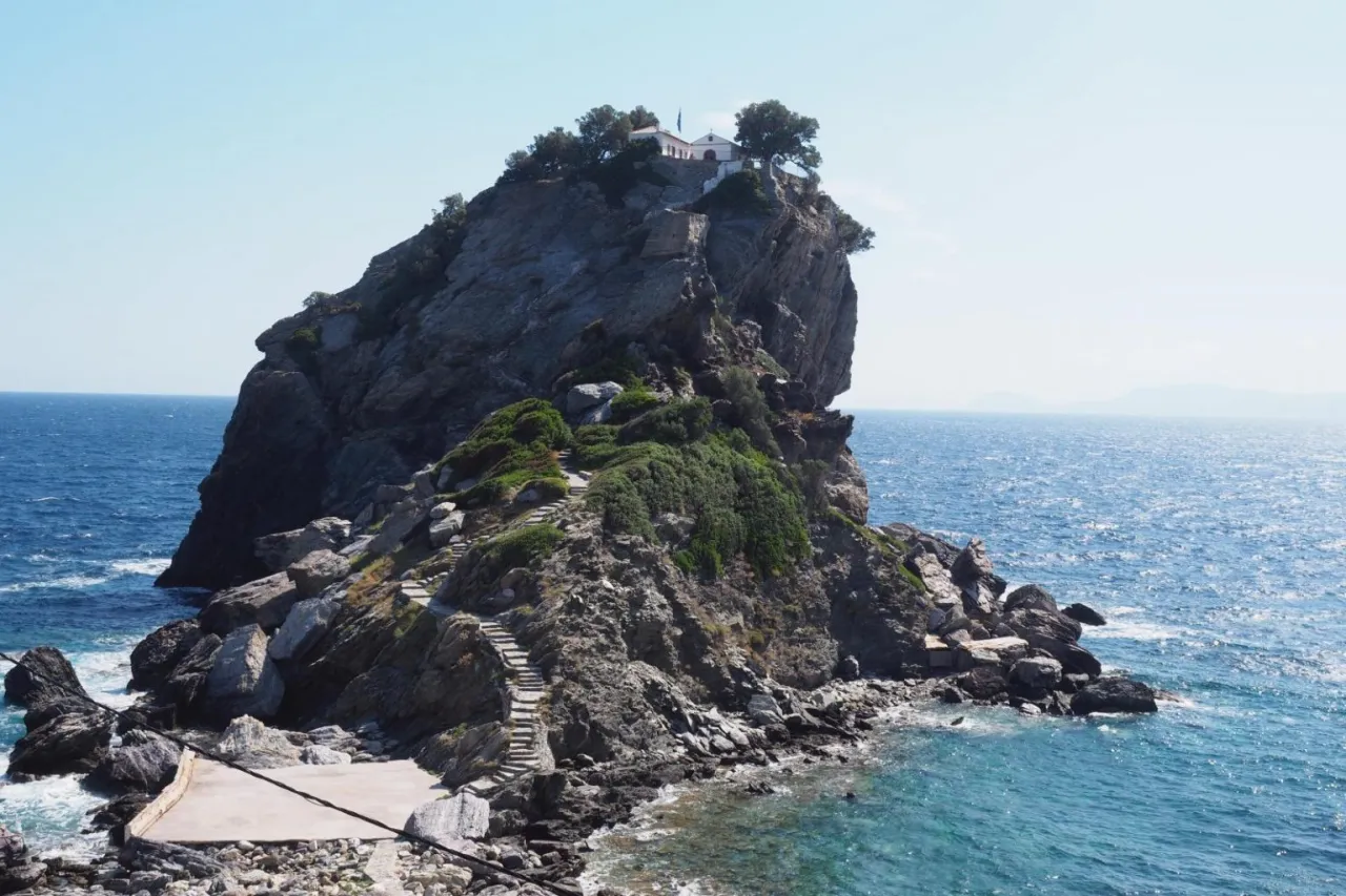 Skała z kościółkiem na szczycie, gdzie kręcono Mamma Mia, z kamiennymi schodami wiodącymi ku górze.