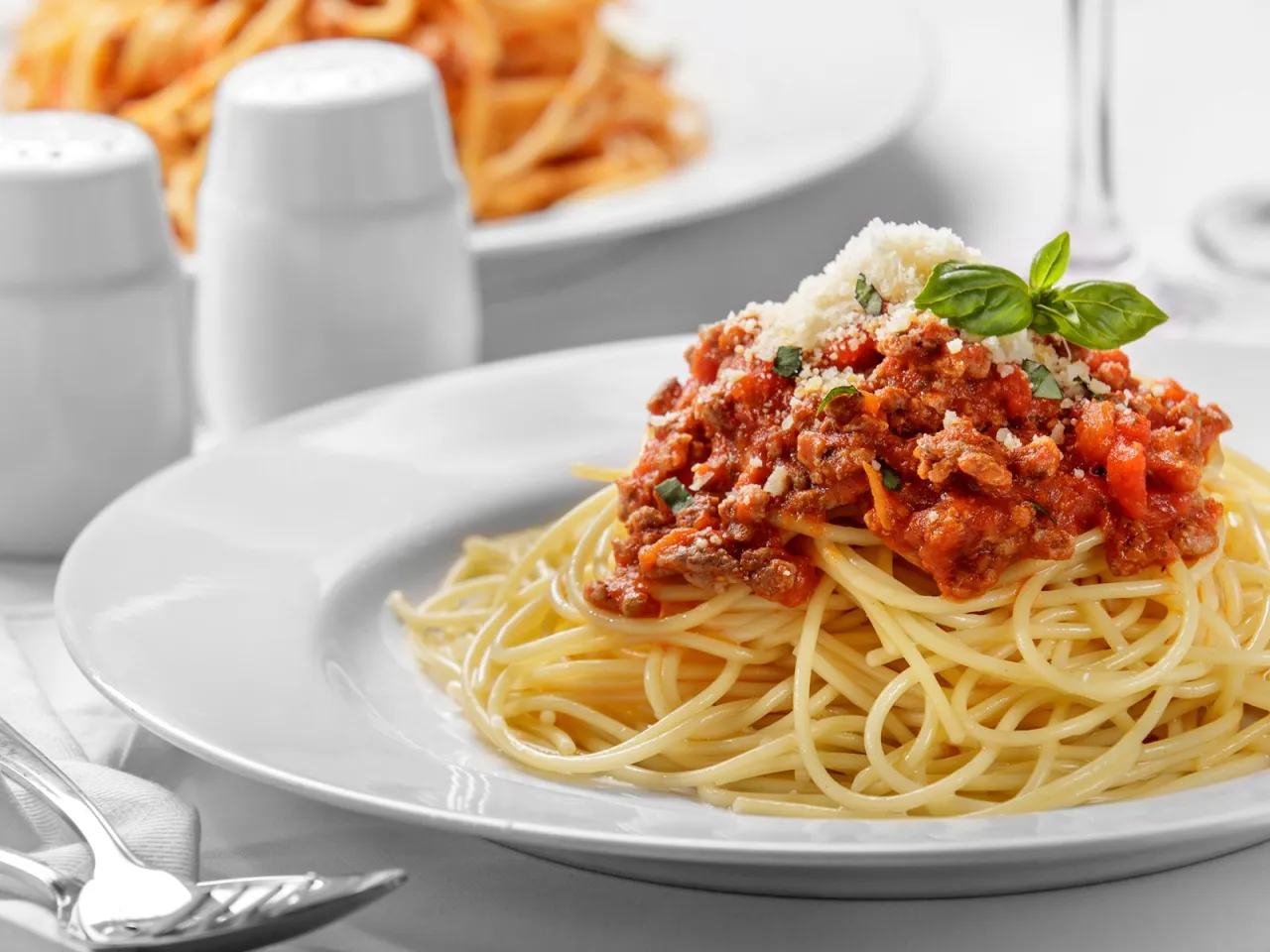 Teller mit Nudeln und Hackfleischso&szlig;e, garniert mit Parmesan und Basilikum