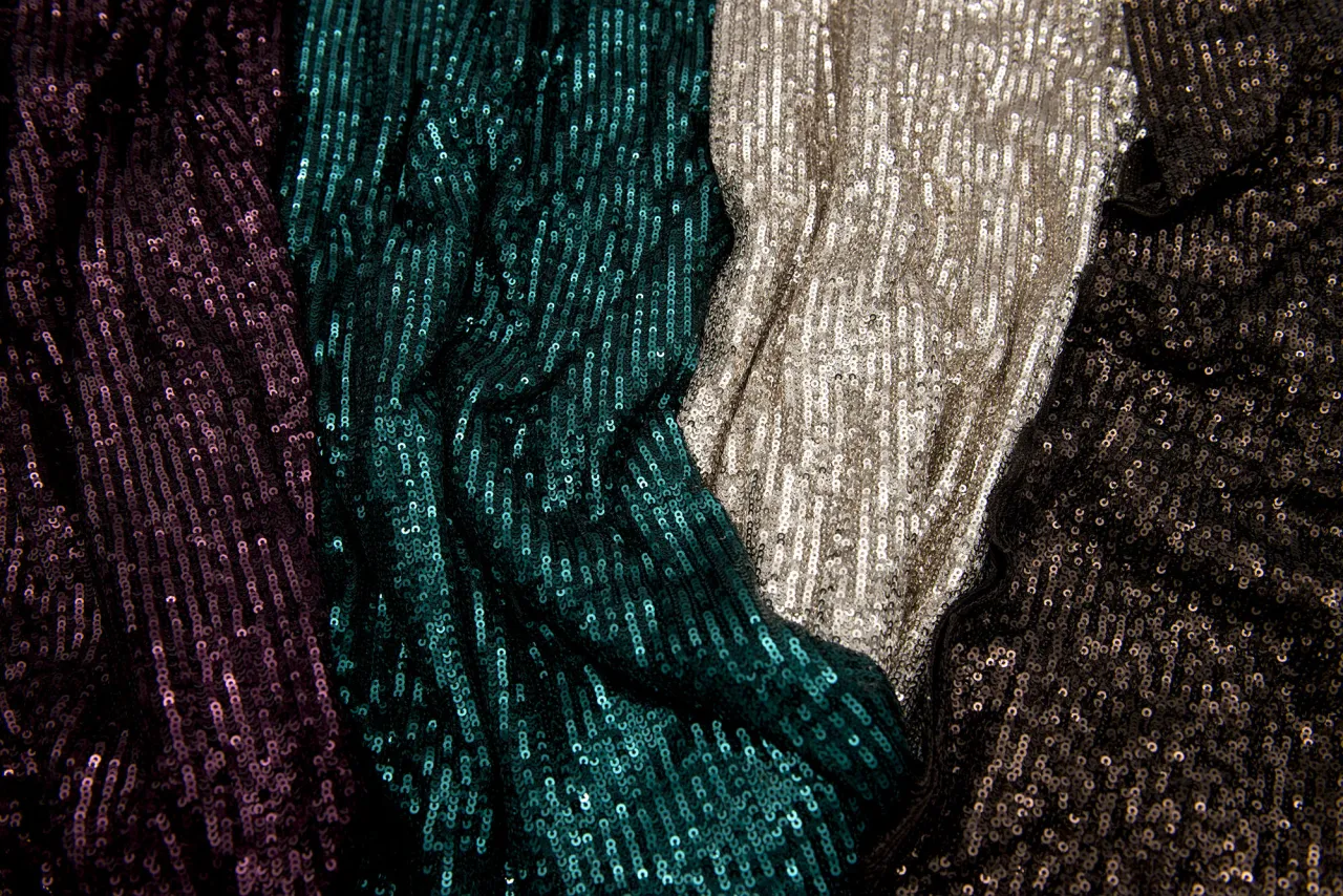 Błyszczące tkaniny w kolorach fioletowym, turkusowym, złotym i czarnym. Idealne do nauki, jak przyszyć cekiny na str&oacute;j wieczorowy.