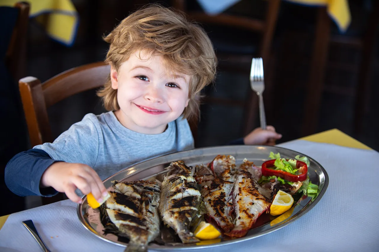 Bambini che mangiano pesce con entusiasmo