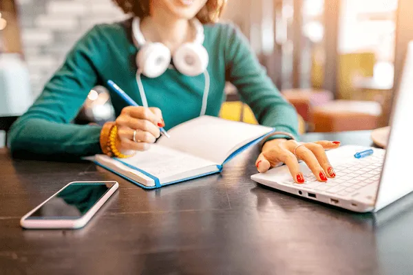 osoba ucząca się języka obcego z słuchawkami i notatkami