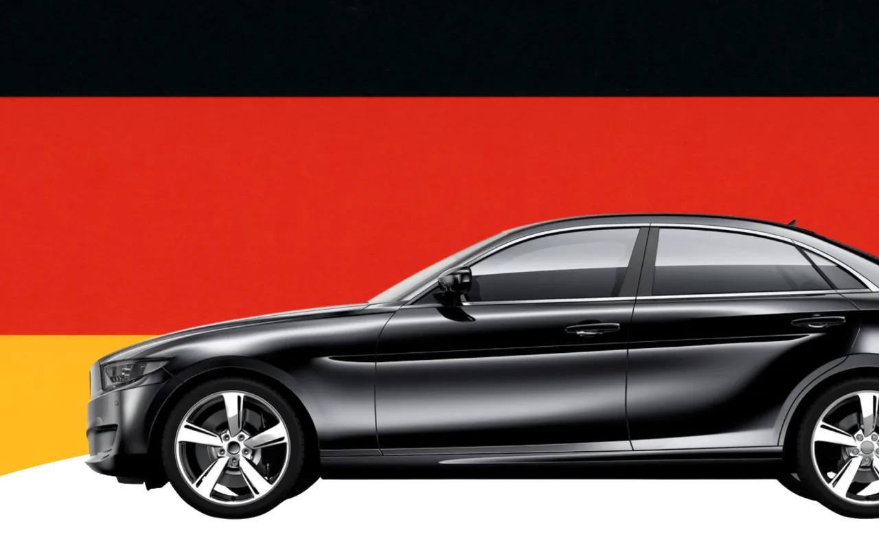 Czarny sedan na tle flagi Niemiec. Tu handlarze kupują auta w Niemczech, szukając okazji.