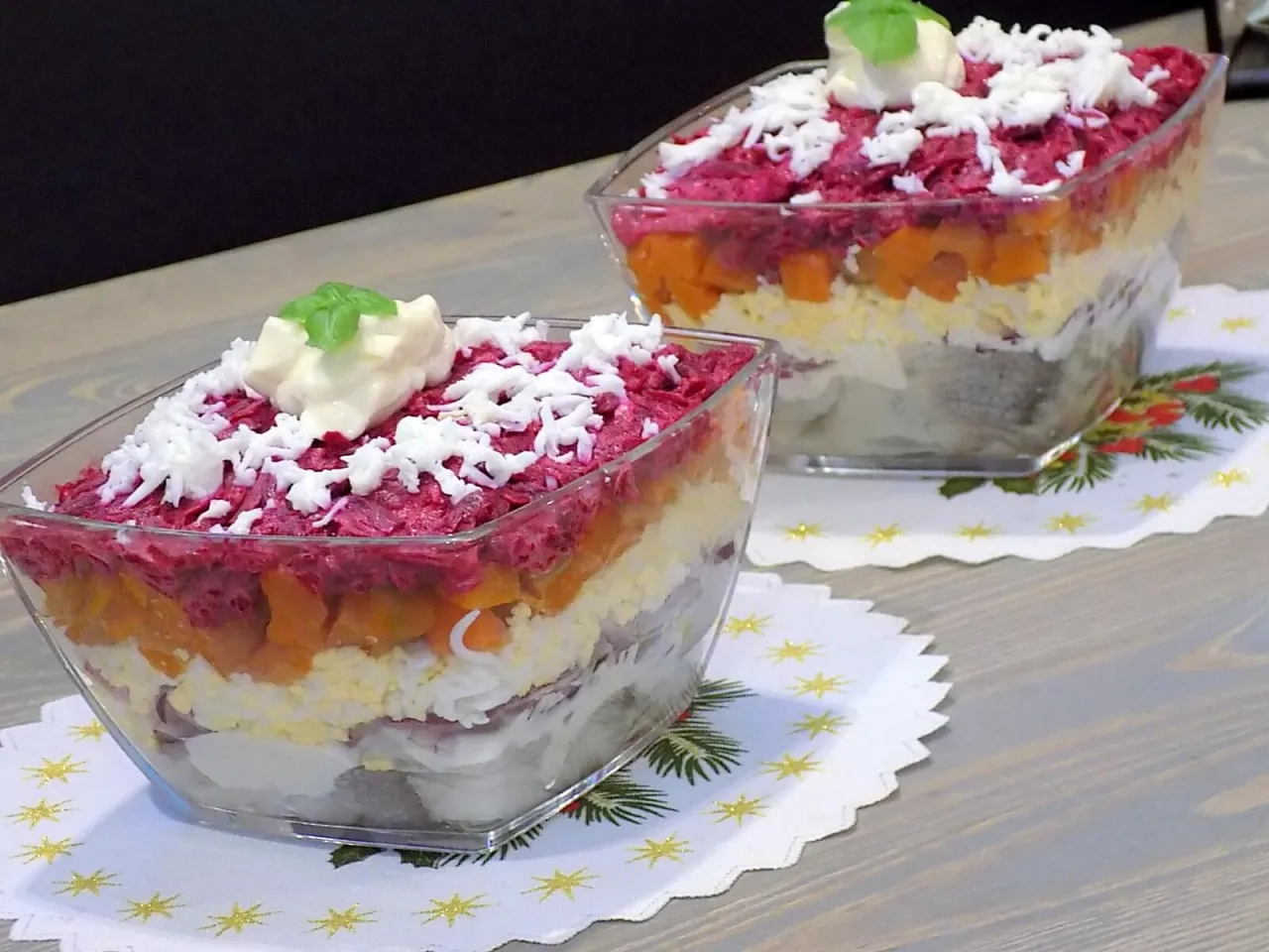 Warstwowa sałatka śledziowa w szklanych misach, idealna na święta. Warstwy śledzia, jajek, marchewki i buraczk&oacute;w.