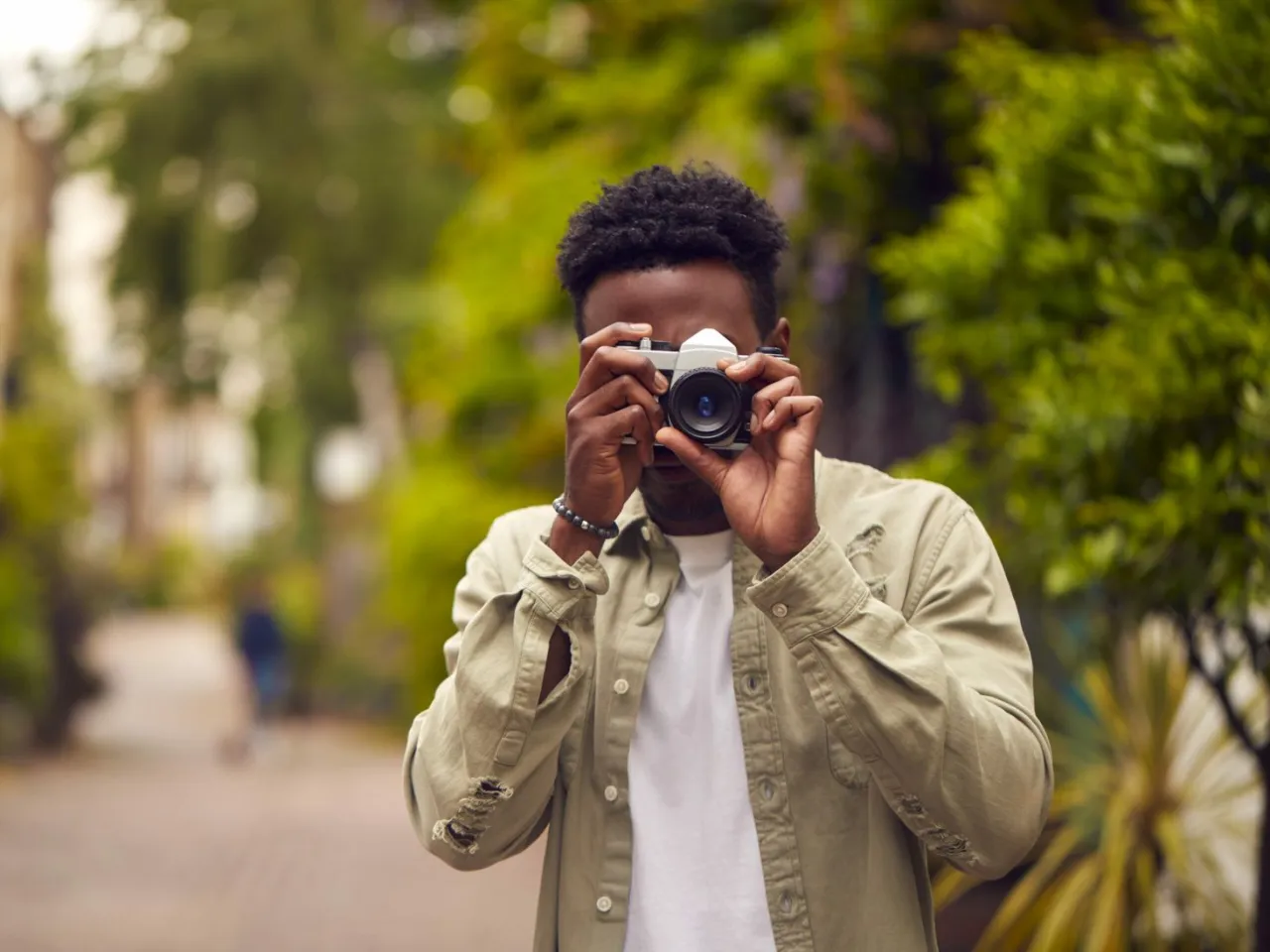 Mężczyzna z aparatem w rękach, zastanawia się, jaka lustrzanka do 2500 zł będzie najlepsza.