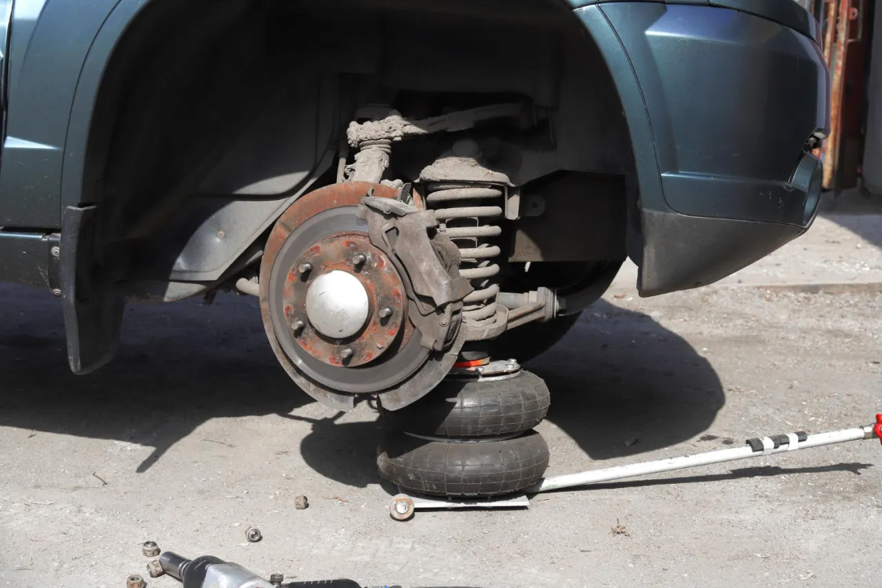 Huczące łożysko to sygnał, że czas na wymianę. Samoch&oacute;d na podnośniku, gotowy do naprawy.