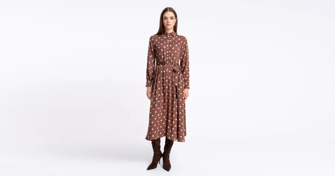 Elegancka brązowa sukienka w groszki z paskiem i zamszowe kozaki to idealna propozycja, jak się ubrać na koncert w filharmonii.