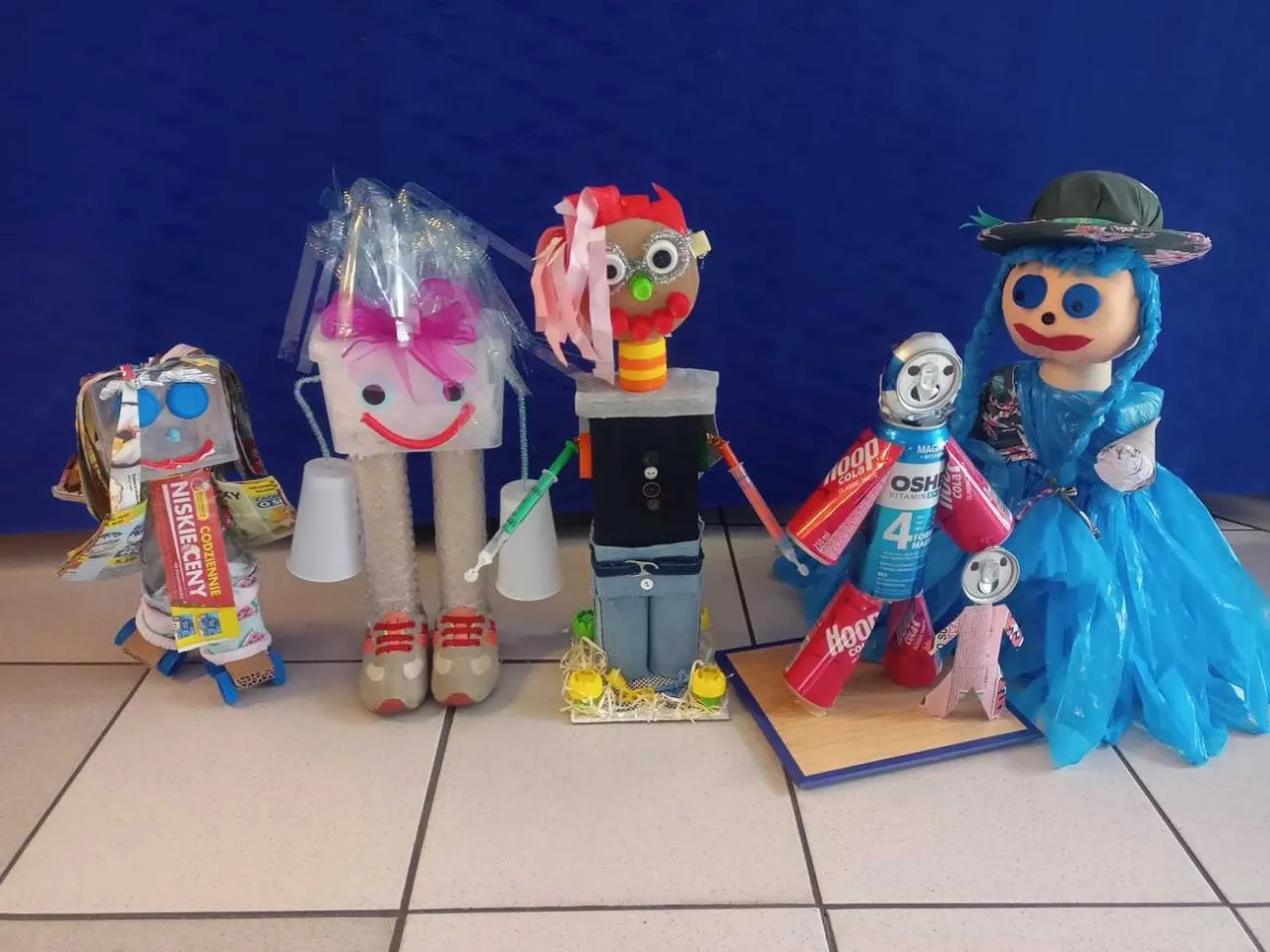 kolorowe ludziki z recyklingu zrobione przez dzieci na wystawie szkolnej