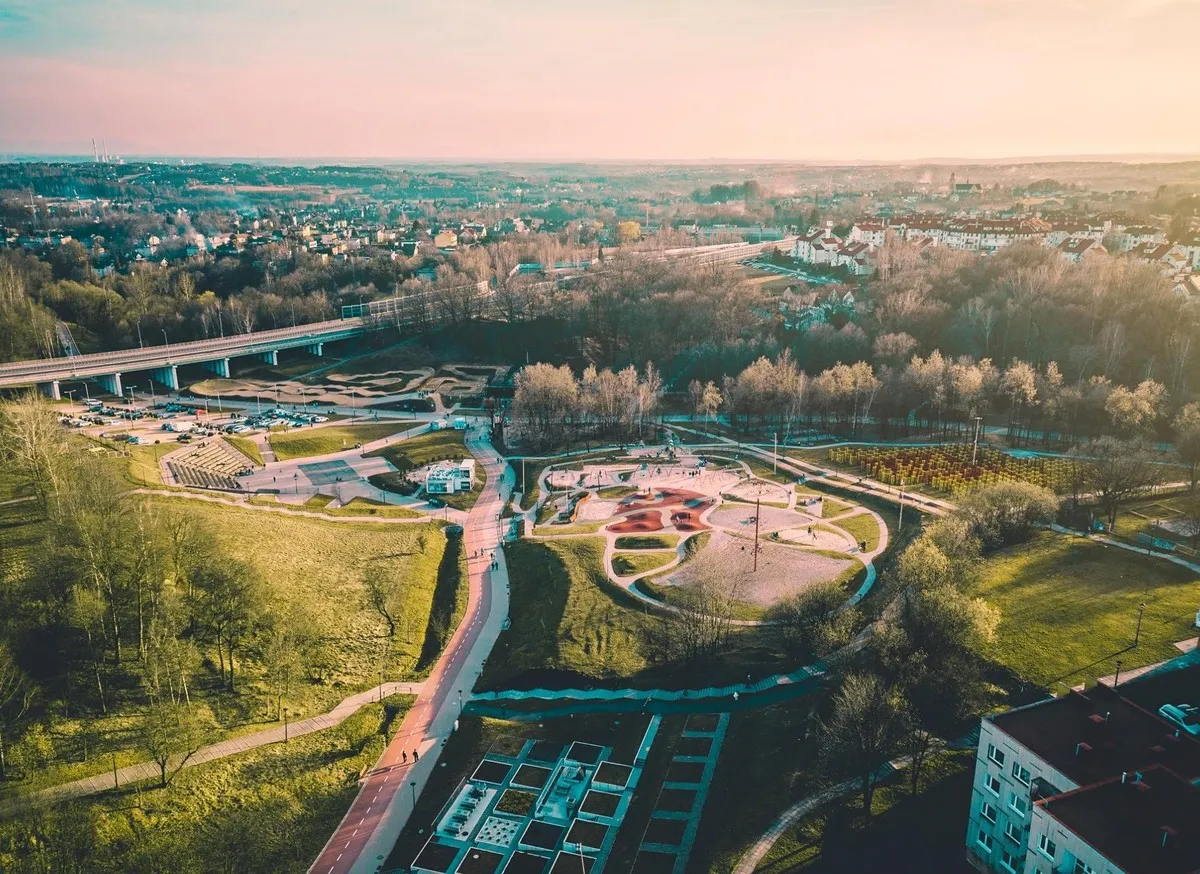 Widok z lotu ptaka na rodzinny park rozrywki Trzy Wzgórza z placem zabaw, ścieżkami i zielenią.
