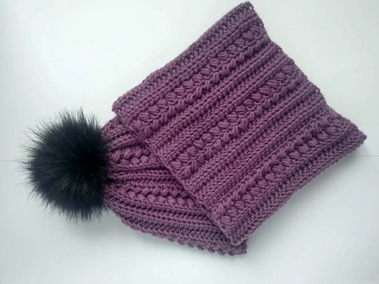 Fioletowa damska czapka na szydełku z puszystym pomponem. Wzór z wypukłymi oczkami, idealny do tutorialu damska czapka na szydełku krok po kroku.