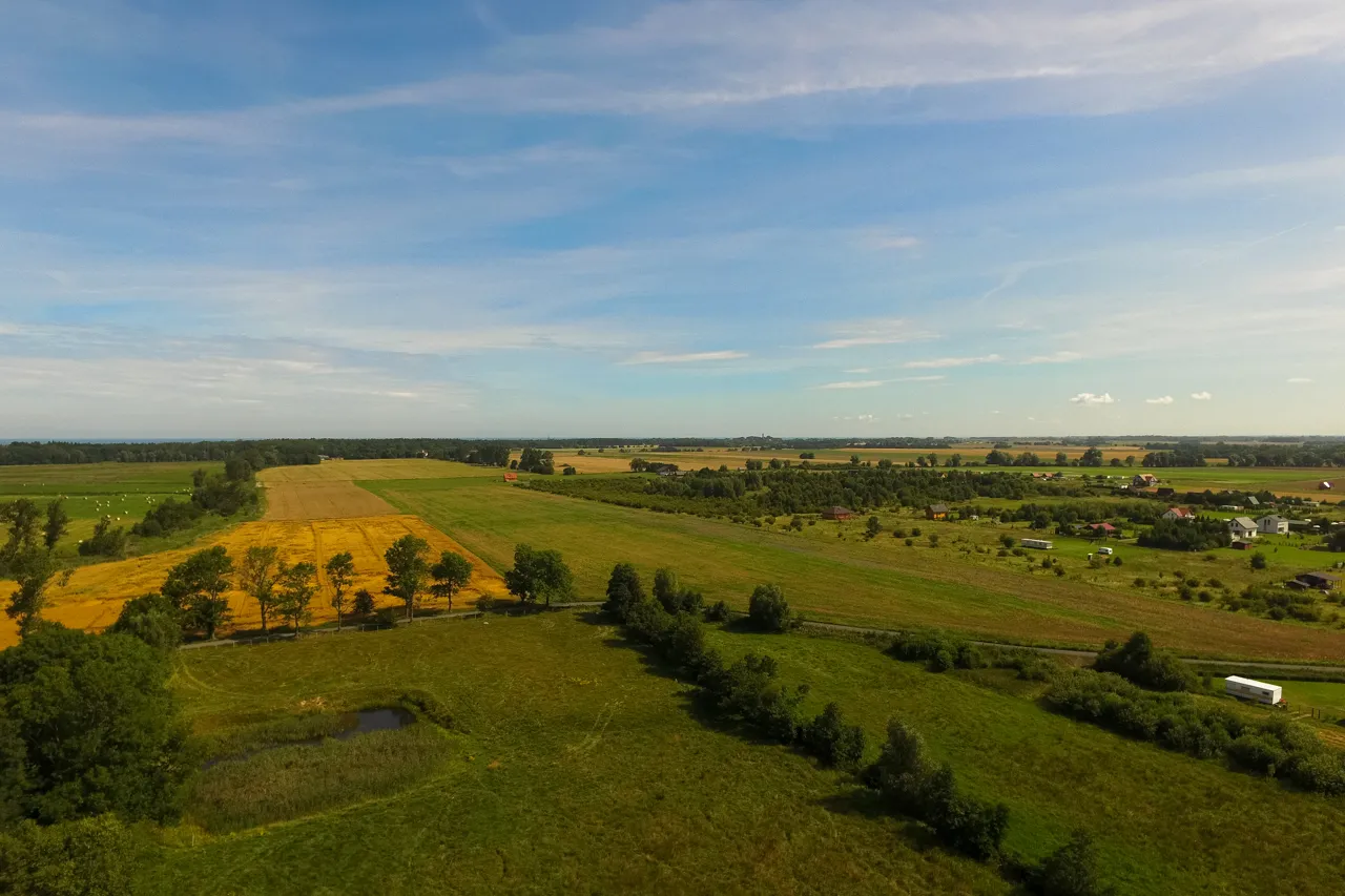 Rozległe pola i łąki, z domami w oddali. Taka działka inwestycyjna co to znaczy? To przyszłość, potencjał i spok&oacute;j.