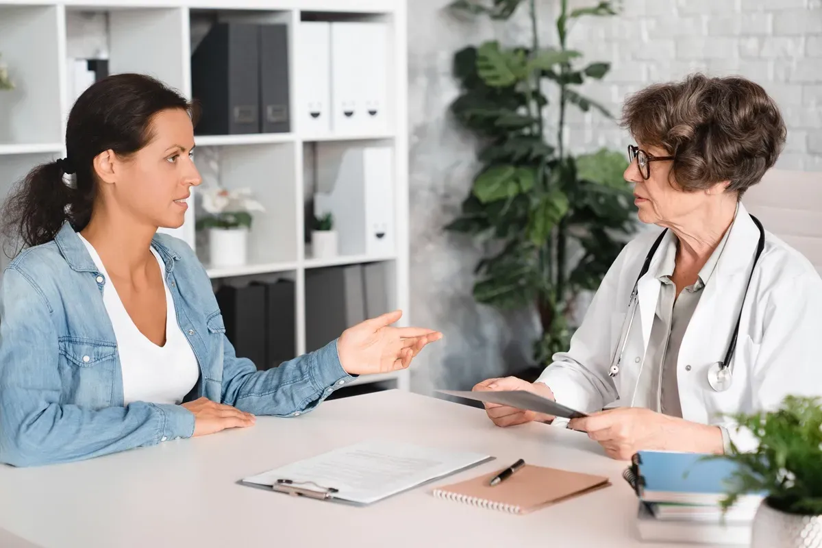 Pacjentka pyta lekarkę, czy podczas rehabilitacji można pracować. Rozmowa w gabinecie lekarskim.