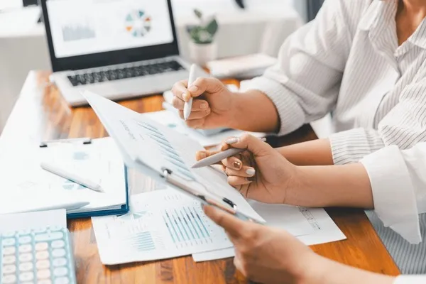 kobieta pracująca przy laptopie z kalkulatorem i notatkami, planująca domowy budżet