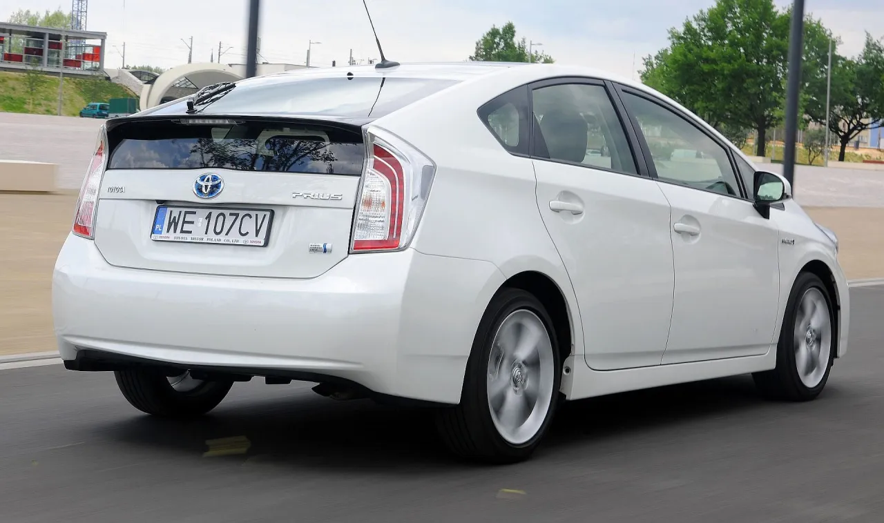 Biały Toyota Prius w ruchu. Czy to lepszy wyb&oacute;r niż Auris?
