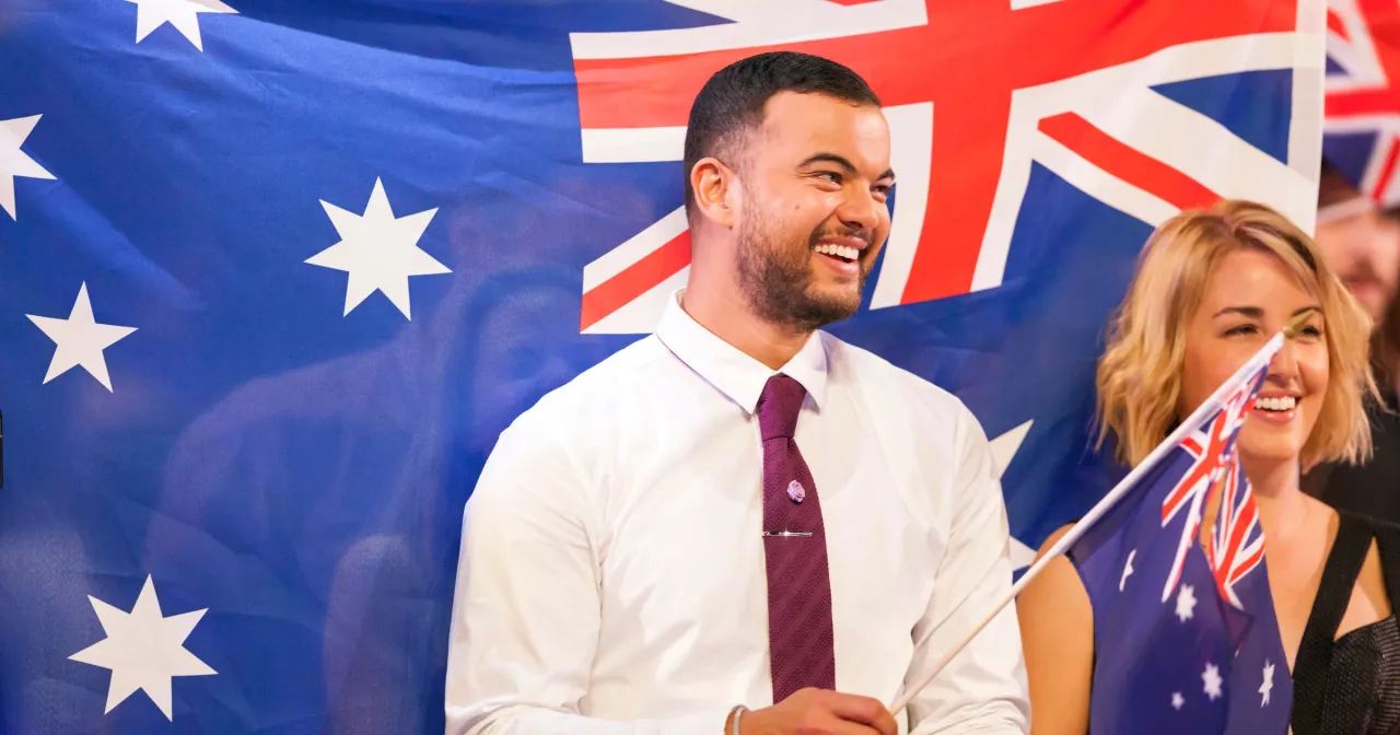 Uśmiechnięci ludzie na tle flagi Australii. Czy Australia jest w Europie? Nie, to kraj na antypodach!