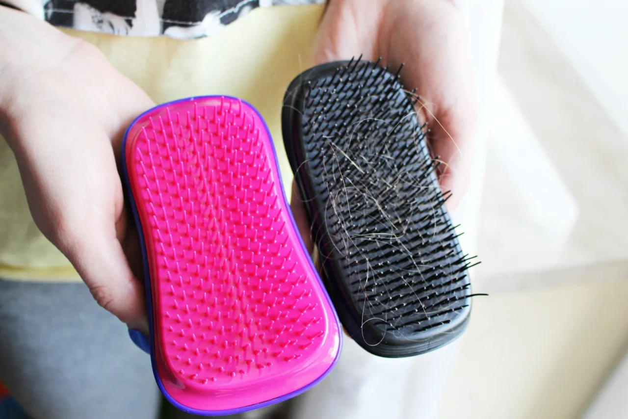 Dwie szczotki do włosów: jedna różowa, czysta, druga czarna, z włosami. Dowiedz się, jak wyczyścić szczotkę do włosów.