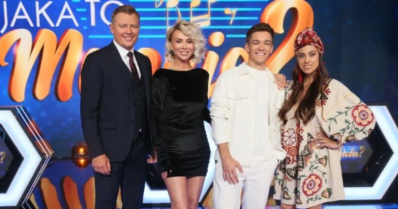 Jaka to melodia piosenkarze: prowadzący i uczestnicy programu w radosnych nastrojach na tle scenografii.