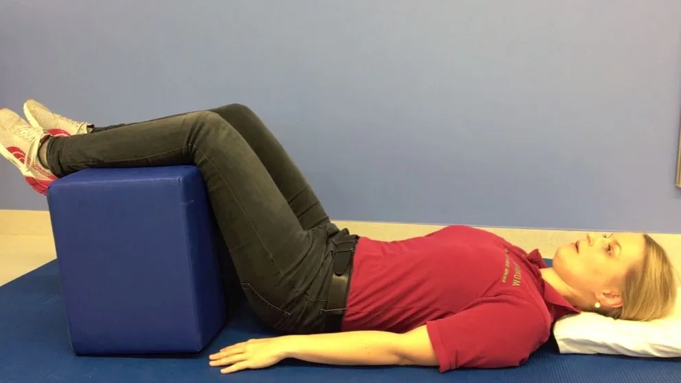 Frau macht Stufenlagerung bei Rückenschmerzen