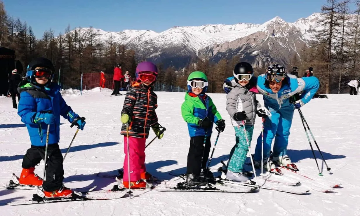 Dzieci uczące się jeździć na nartach w szkółce