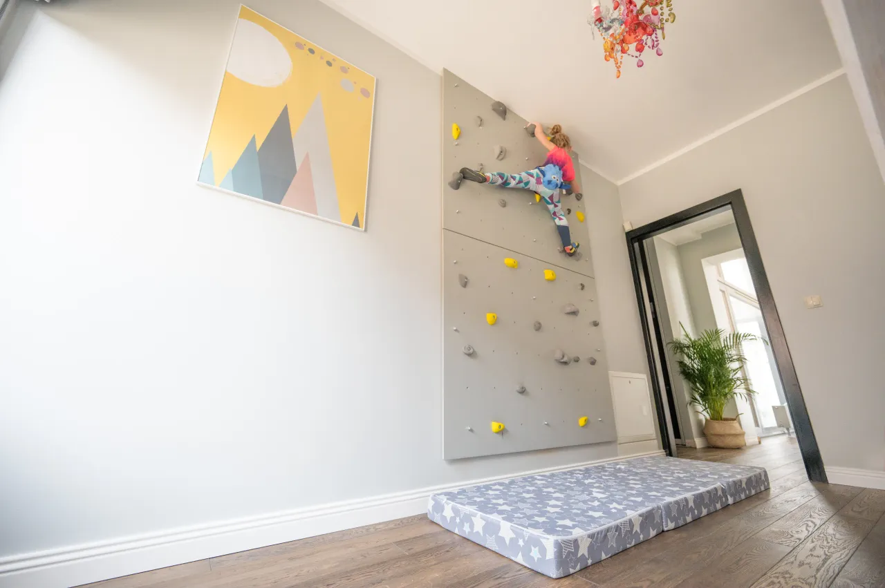 Dziecko wspina się po domowej ściance wspinaczkowej. To świetny pomysł, jak zrobić ściankę wspinaczkową dla dzieci.
