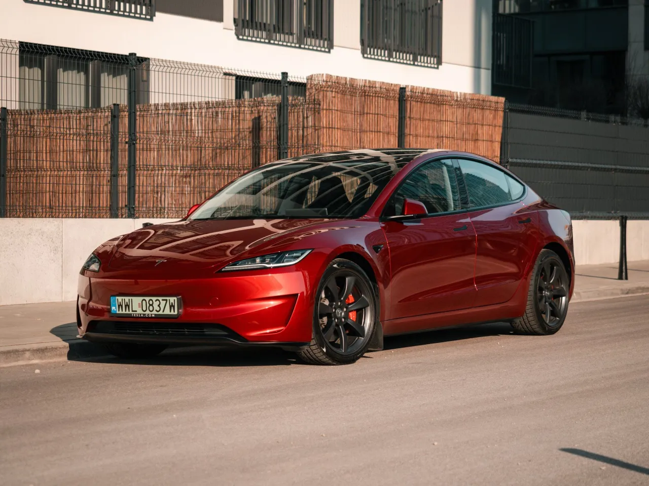 Czerwona Tesla Model 3, zgrabna i sportowa, gotowa do jazdy. Zastanawiasz się, ile koni ma ten model?