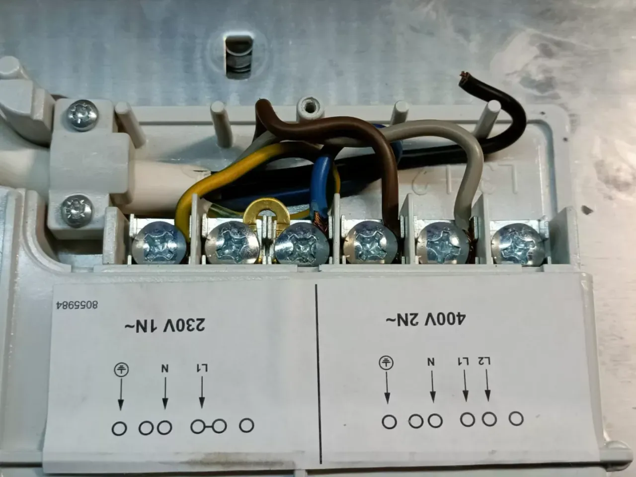 Wewnątrz płyty indukcyjnej, gdzie jest bezpiecznik? Widoczne są zaciski do podłączenia przewod&oacute;w zasilających.