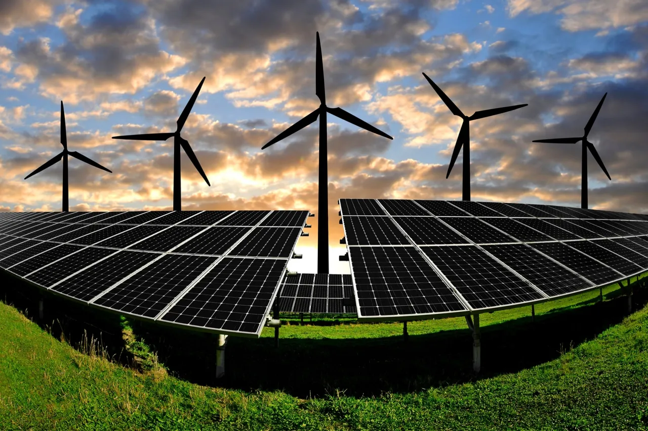 Wiatraki i panele słoneczne na tle zachodzącego słońca. Nowelizacja ustawy o OZE to krok w stronę zielonej energii.