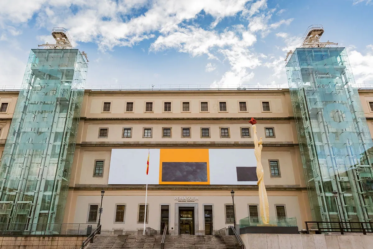 Muzeum Narodowe Centrum Sztuki Kr&oacute;lowej Zofii w Madrycie, z nowoczesnymi szklanymi windami i rzeźbą.