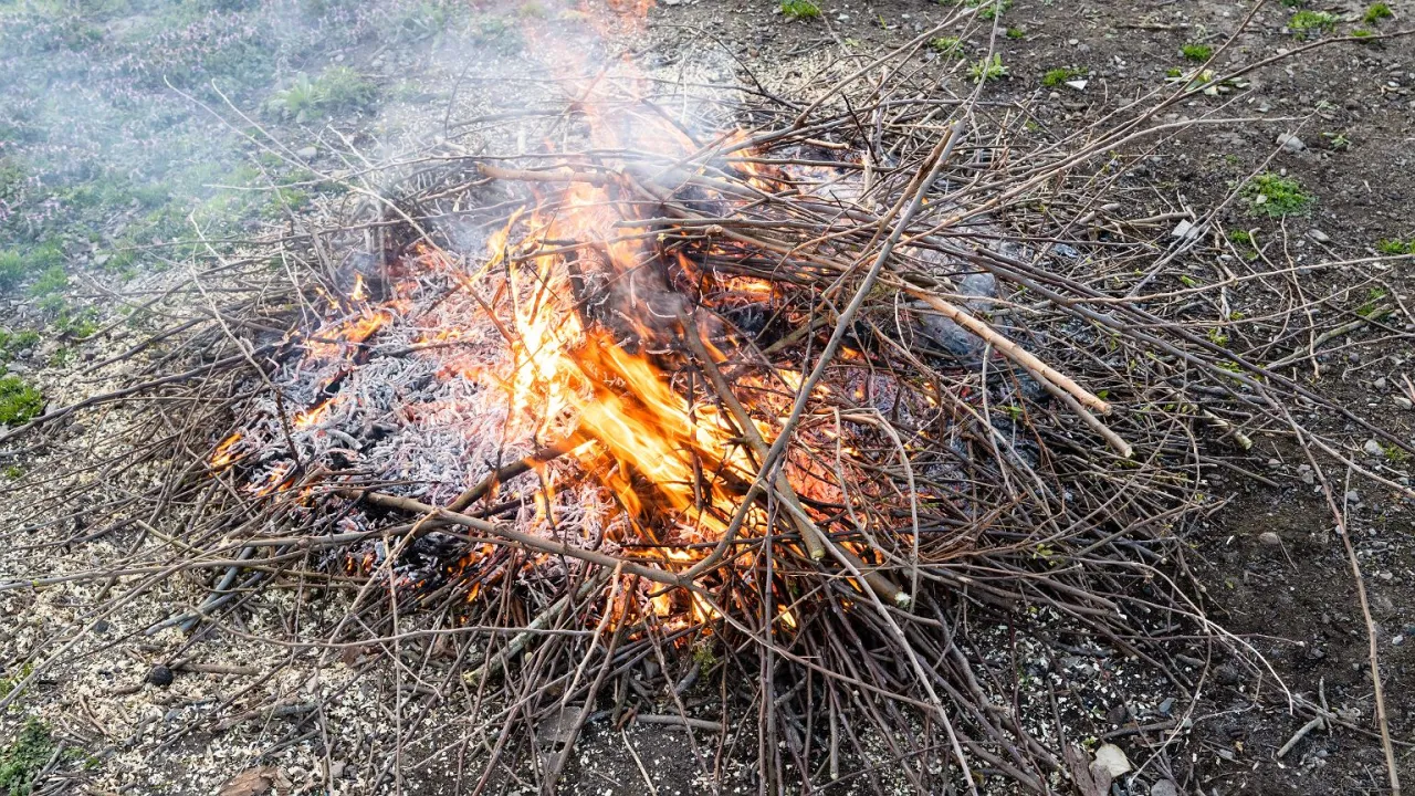 Osoba rozpalająca ognisko w deszczu pod osłoną