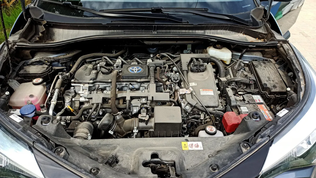 Silnik Toyoty C-HR. Akumulator znajduje się po prawej stronie, pod czarną osłoną.