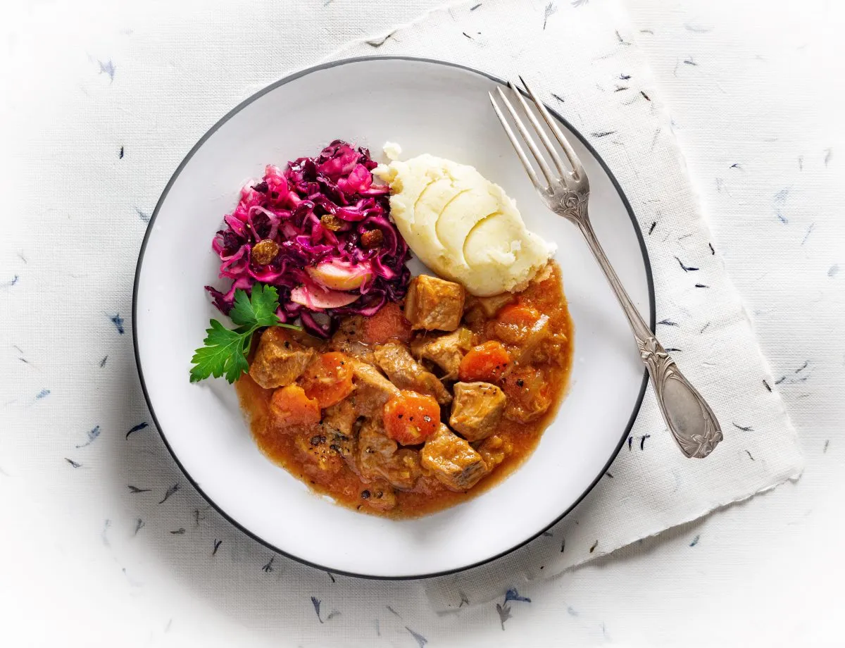 Gulasz wieprzowy z marchewką, puree ziemniaczanym i czerwoną kapustą. Kiedy solić mięso wieprzowe na gulasz? Najlepiej przed smażeniem, by wydobyć smak.