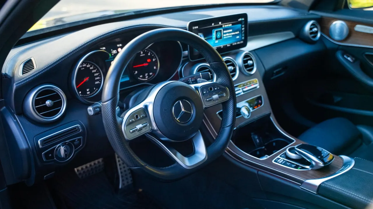Wnętrze Mercedesa C 220 d: kierownica, deska rozdzielcza z ekranem multimediów i drewnianymi wstawkami.