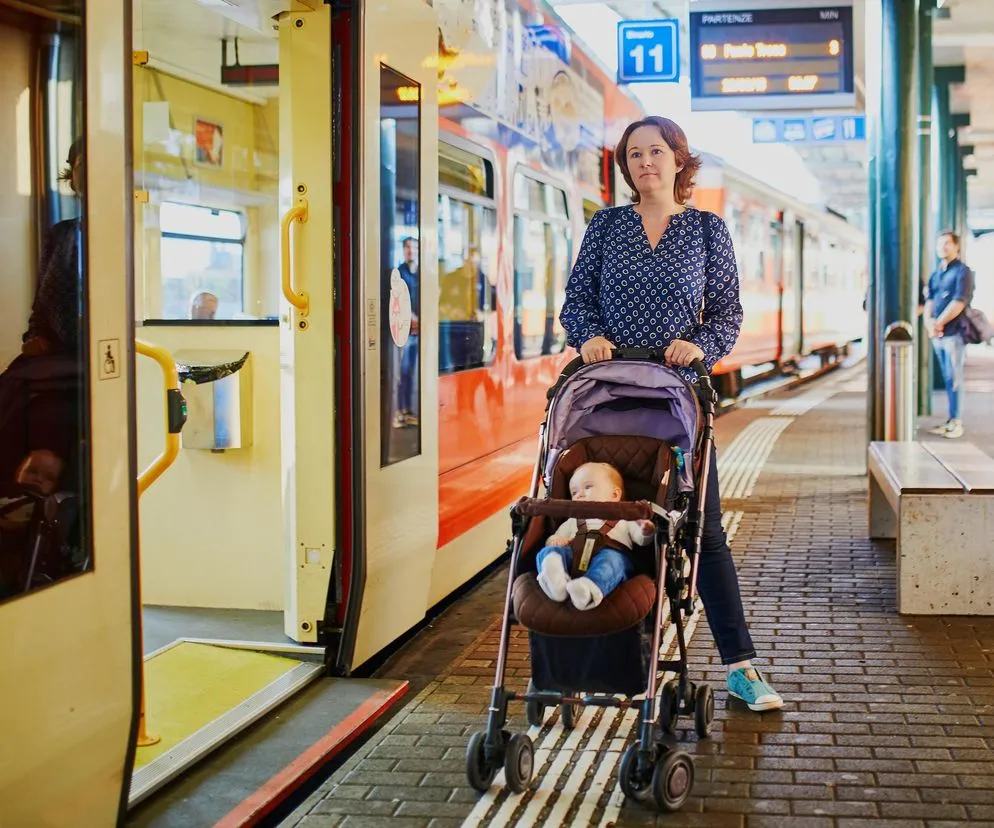 Rodzic wsiadający z w&oacute;zkiem do pociągu