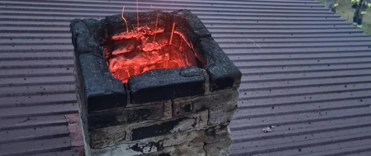 Żarzący się komin, z którego lecą iskry, sugeruje, że coś się pali w środku. Może to być przyczyną, dlaczego lecą iskry z komina.
