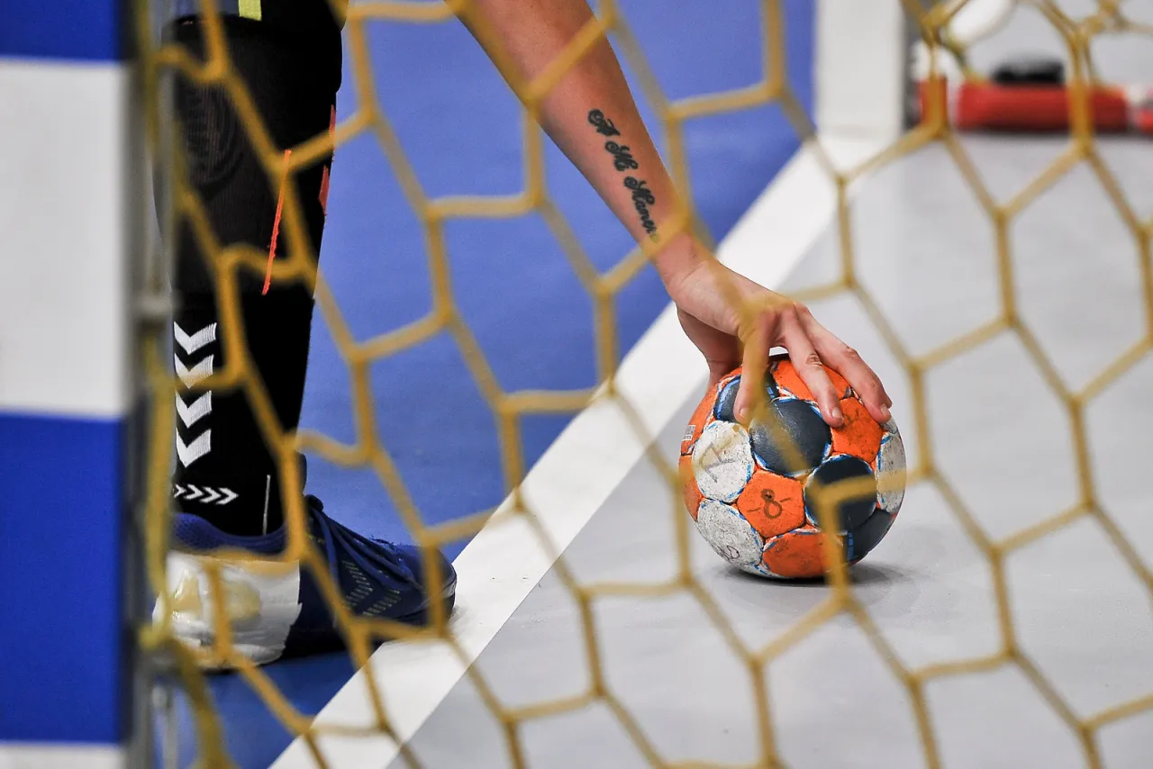 Piłkarz ręczny z tatuażem na przedramieniu trzyma piłkę. Czy zastanawiałeś się, ile trwa połowa w piłce ręcznej?