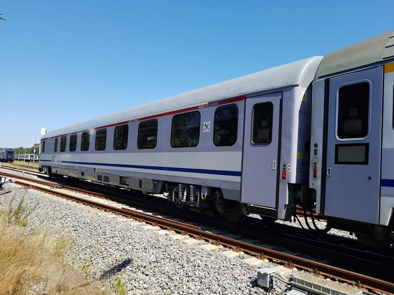 Pociąg TLK z wagonem restauracyjnym (wars) stoi na torach.
