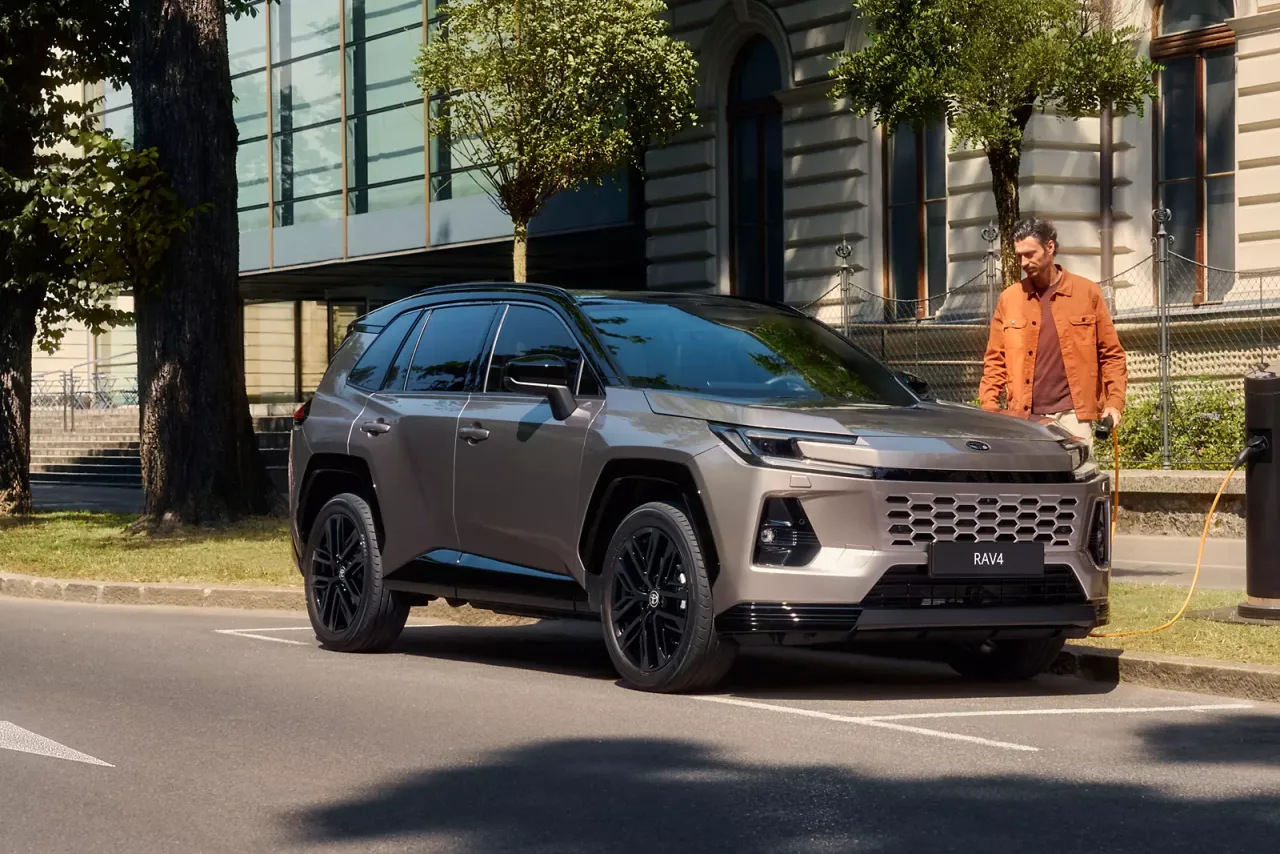 Mężczyzna ładuje swojego nowego, brązowego SUV-a. Zastanawiasz się, ile kosztuje Toyota RAV4?