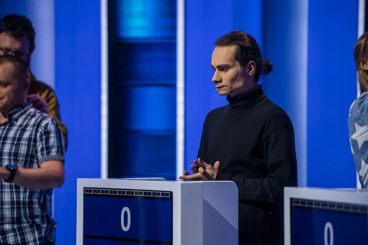 Mężczyzna w czarnym golfie czeka na swoją kolej, by zdobyć jeden z dziesięciu ile można zdobyć punkt&oacute;w.