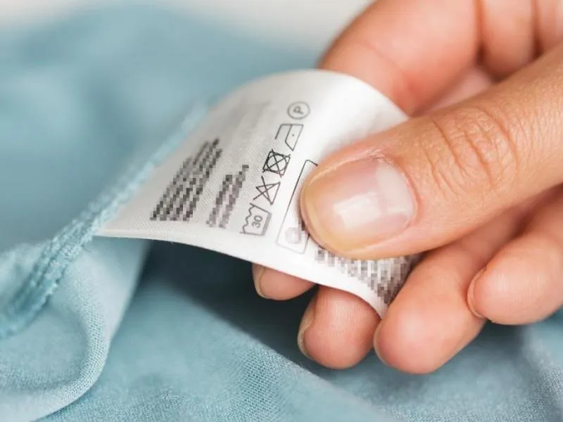 dziecko mierzy ubranie w sklepie, rodzic sprawdza metkę