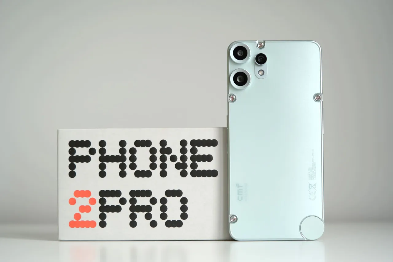 Jasny, miętowy telefon z potrójnym aparatem obok pudełka z napisem 