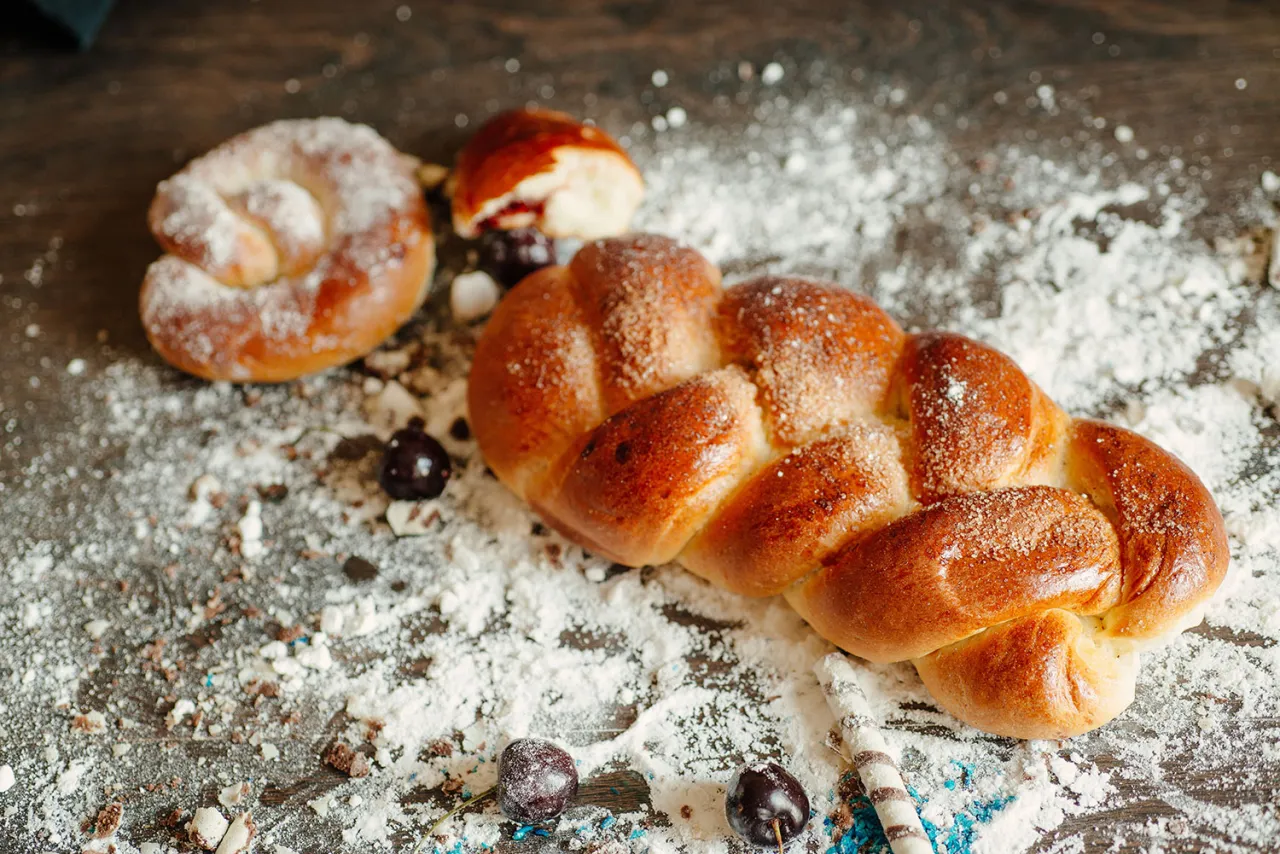 Pyszna chałka bezglutenowa przepis na puszyste, złociste wypieki. Idealna na śniadanie, posypana cukrem i otoczona wiśniami.
