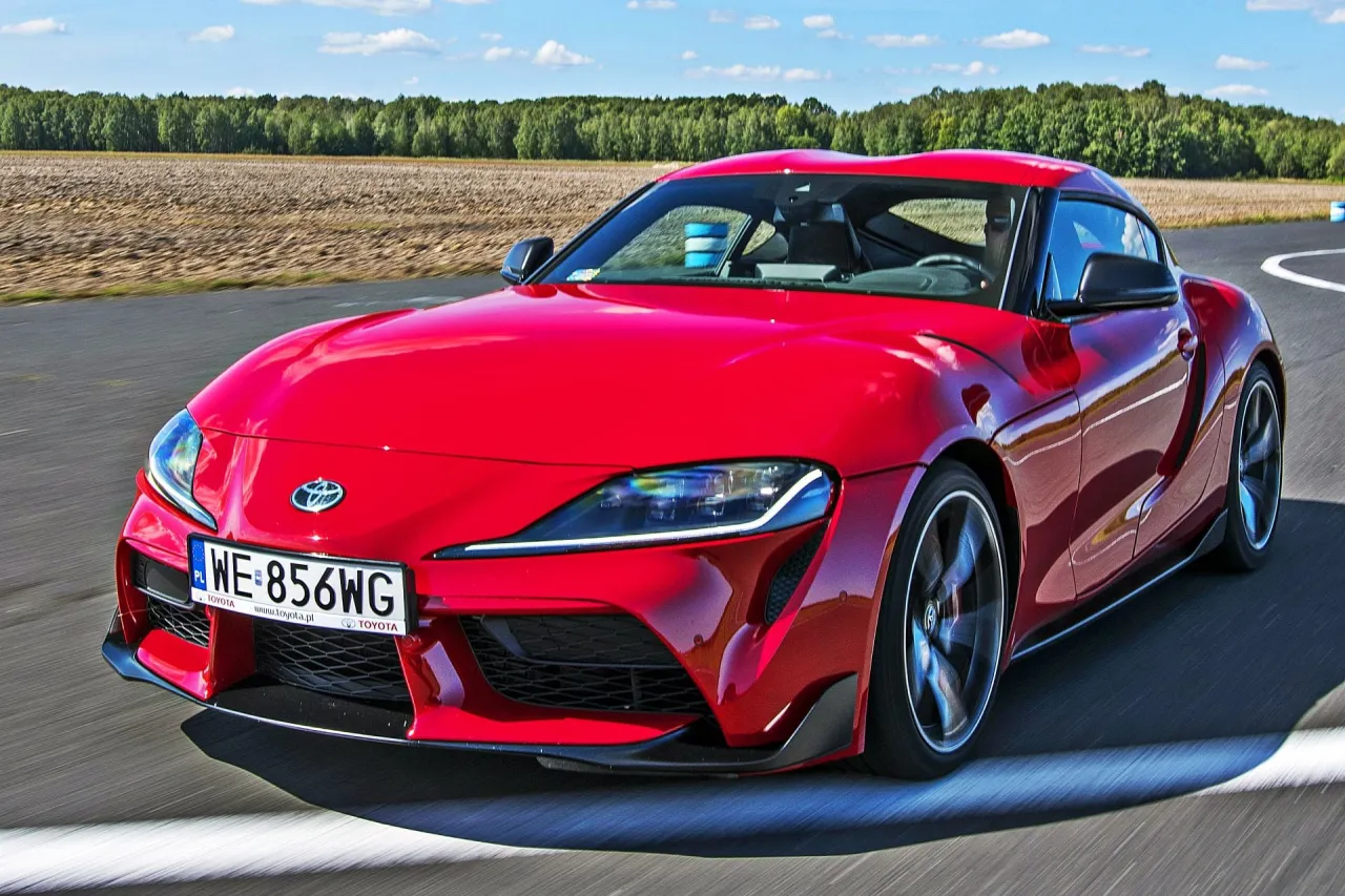 Czerwona Toyota Supra na torze. Zastanawiasz się, ile kosztuje Toyota Supra? Ten sportowy samoch&oacute;d zachwyca wyglądem i osiągami.