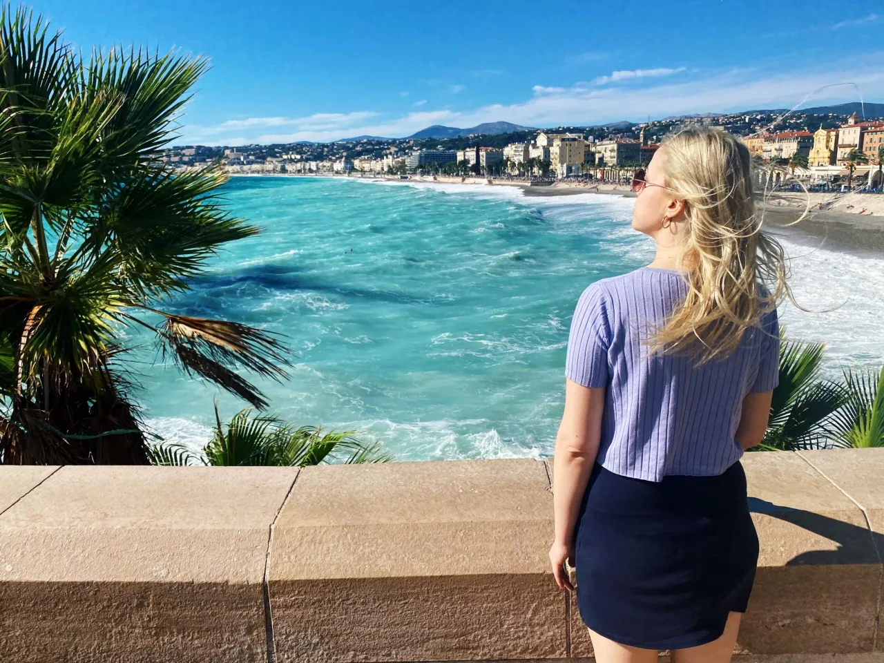 Kobieta podziwia turkusowe morze i panoramę miasta na riwierze francuskiej.