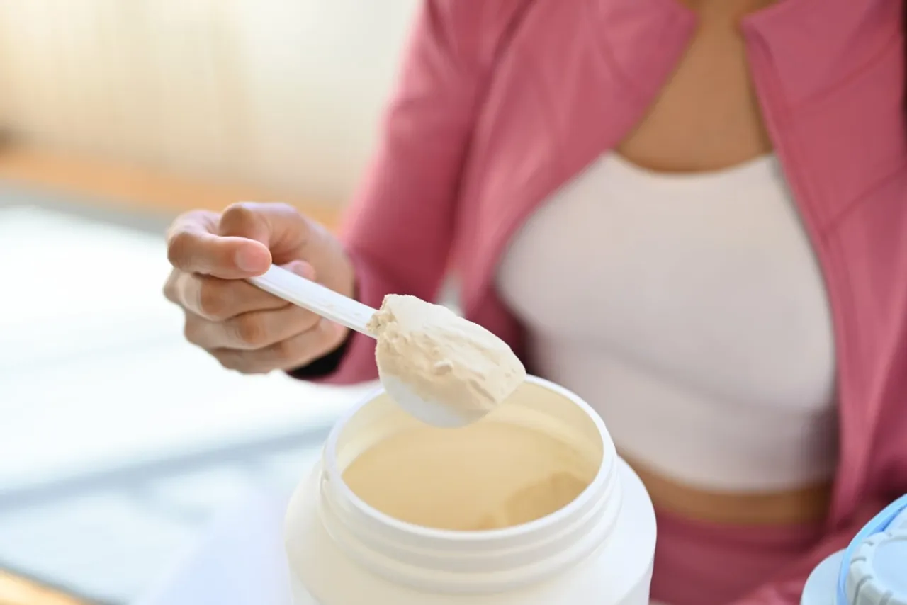 Dłoń nabiera miarkę odżywki białkowej. Czy to przed czy po treningu?