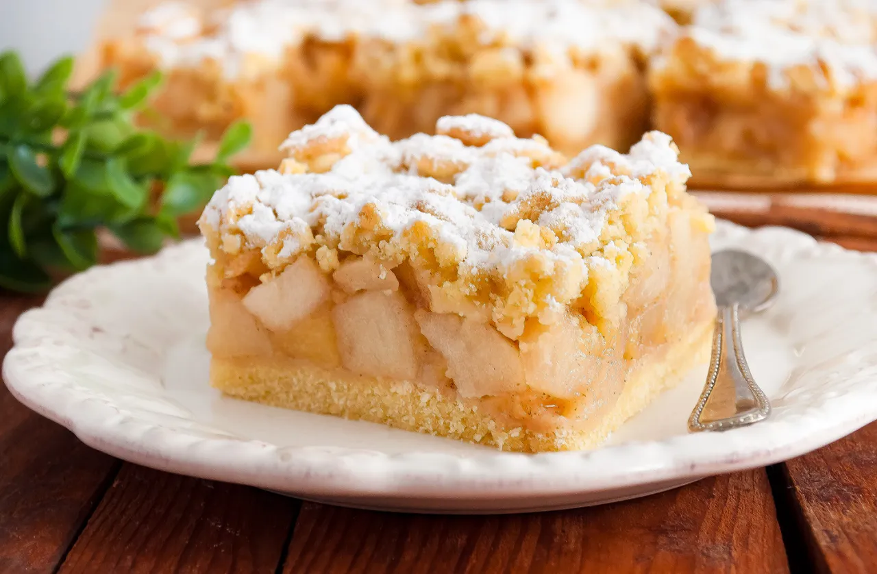 Pyszna szarlotka przepis na kruchym cieście z jabłkami i kruszonką, posypana cukrem pudrem. Idealna na deser.