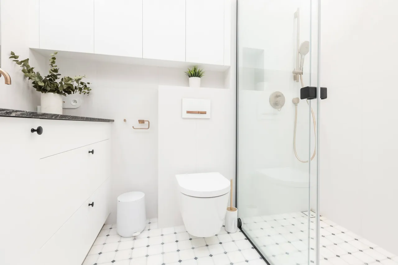 Nowoczesna łazienka w bloku: toaleta, prysznic i szafki. Zastanawiasz się, ile kosztuje remont łazienki w bloku?