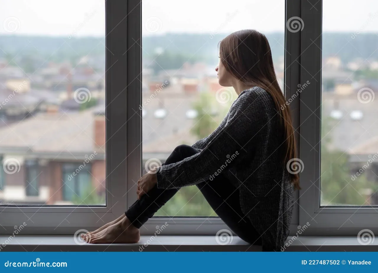 osoba samotnie patrząca przez okno podczas gdy inni się bawią