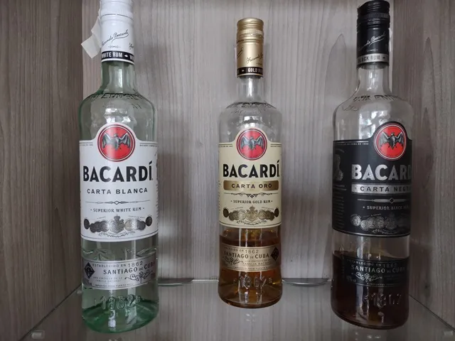 Różne butelki rumu Bacardi na tle koktajli
