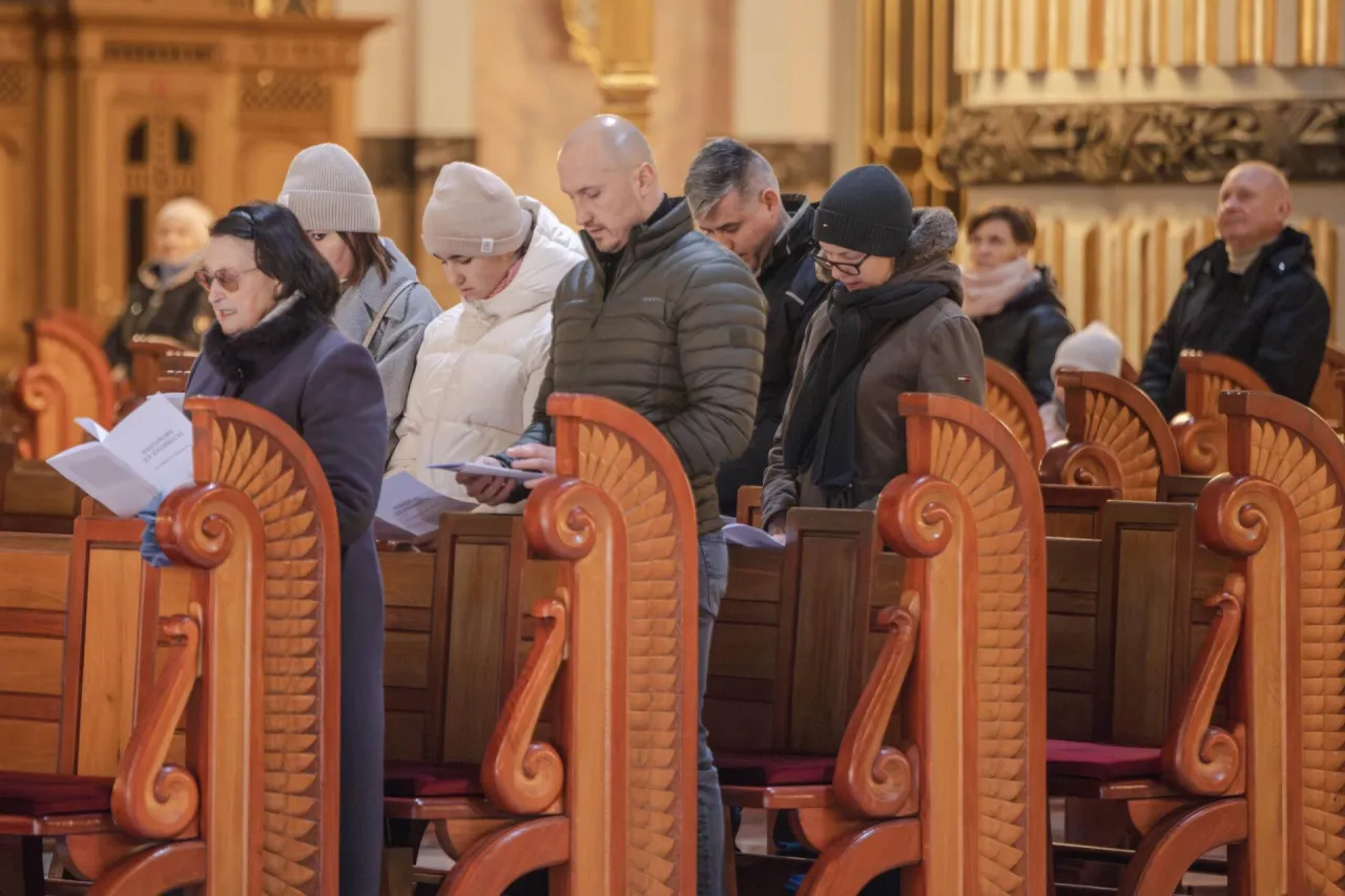 Ludzie w kościele czytają modlitwy podczas nieszporów za zmarłego.