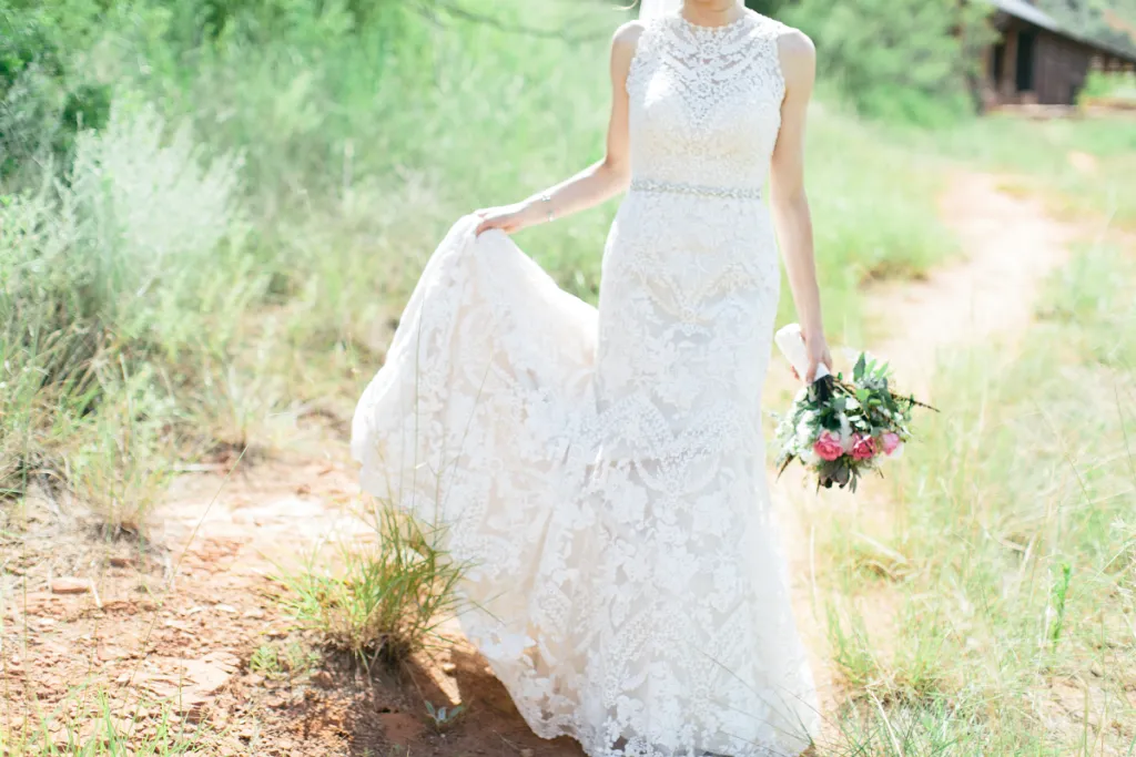 Panna młoda z świadkową podpinająca tren sukni ślubnej